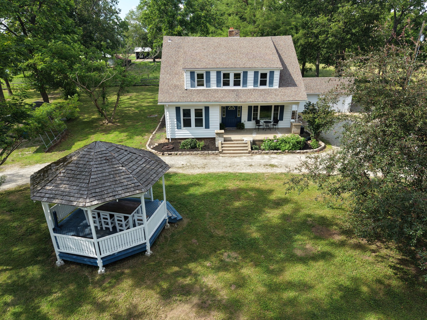 Aerial of white farmhouse with blue shutters and gazebo - HelixMind Real Estate Media