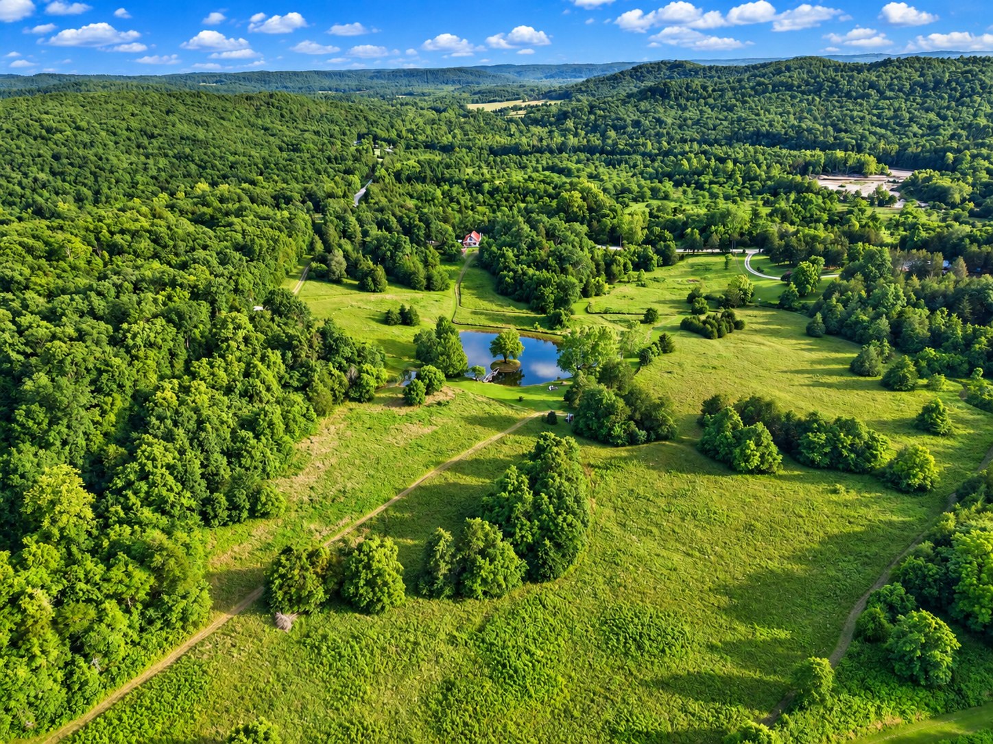 Aerial of rolling farmland with house and pond - HelixMind Real Estate Media