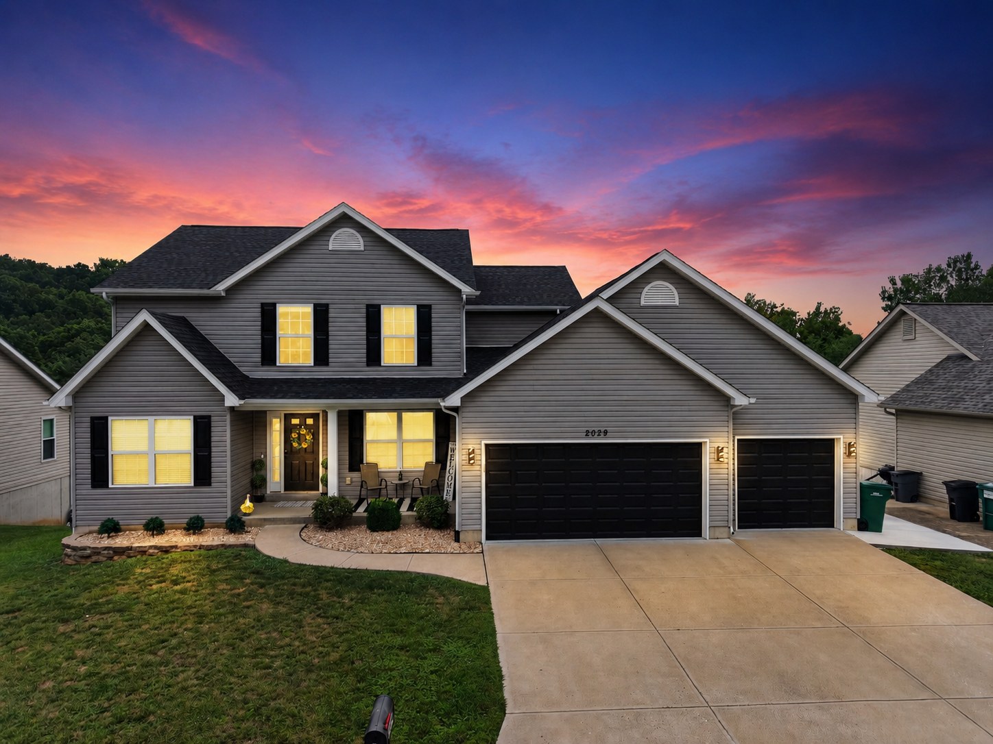 Modern gray home with three-car garage at twilight - HelixMind Real Estate Media